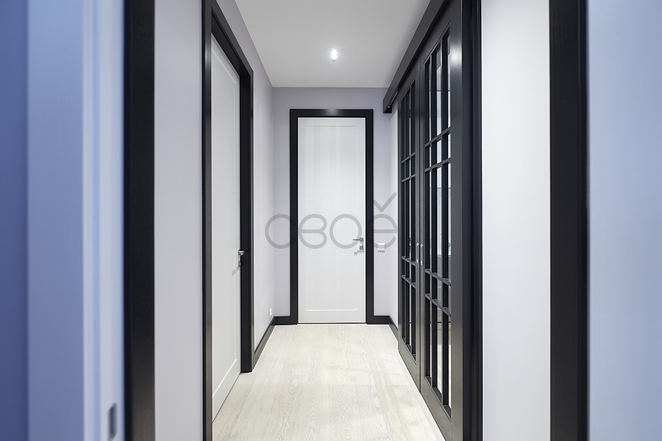 Стильные белые межкомнатные двери в обрамлении черных наличников
